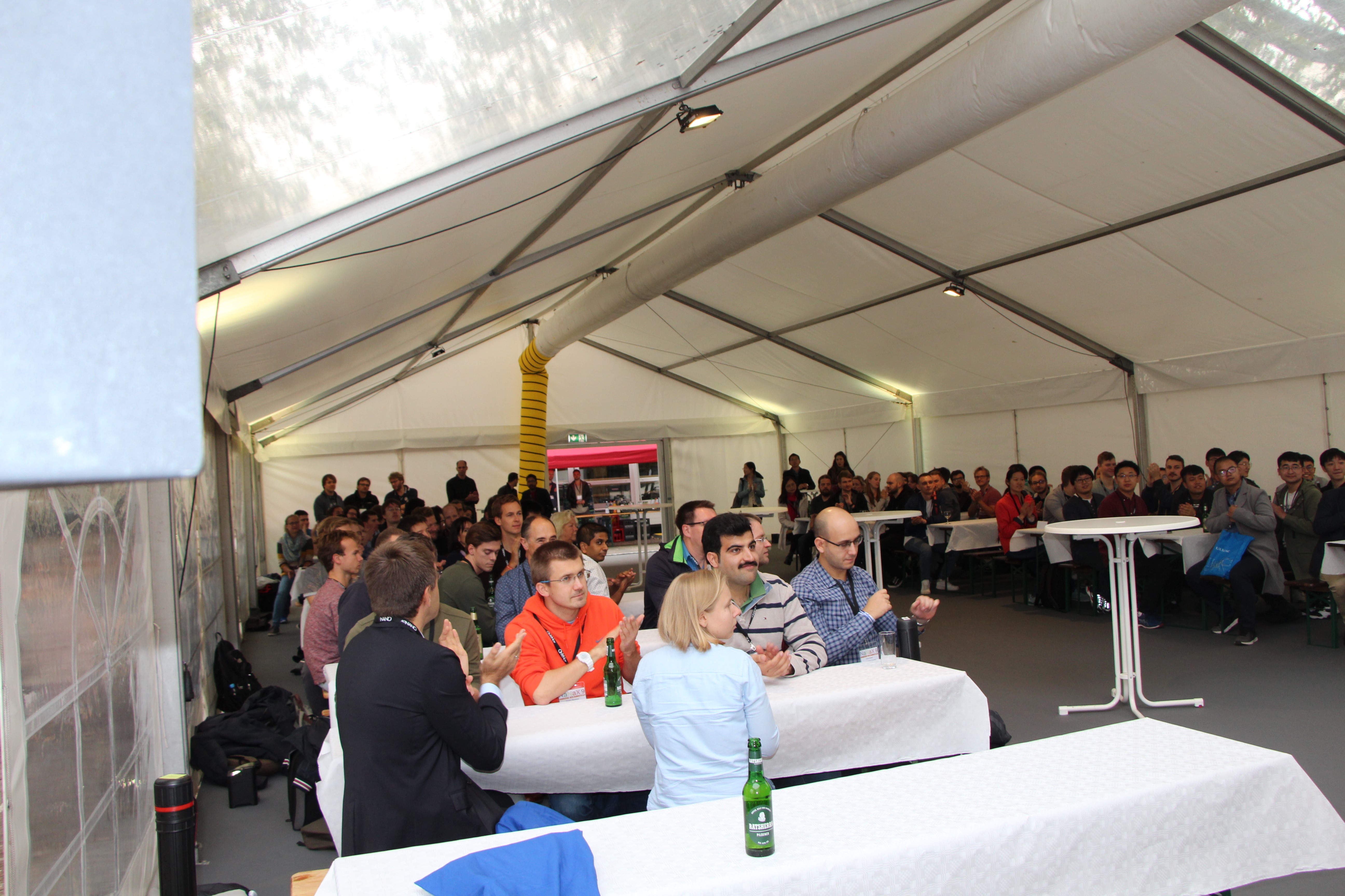 Picture from the workshop with people gathering in a big tent and sitting at tables